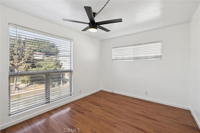 spare room featuring dark wood-style floors, baseboards, and a ceiling fan