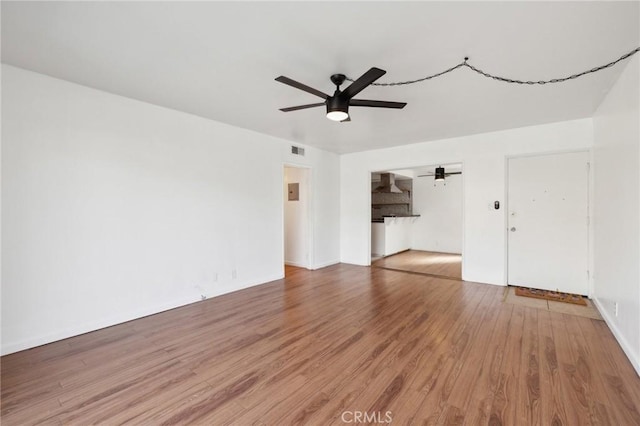 unfurnished living room featuring a ceiling fan, visible vents, and wood finished floors