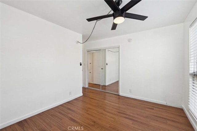 spare room with dark wood-style floors, ceiling fan, and baseboards