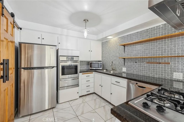 kitchen featuring appliances with stainless steel finishes, a barn door, a sink, and white cabinetry