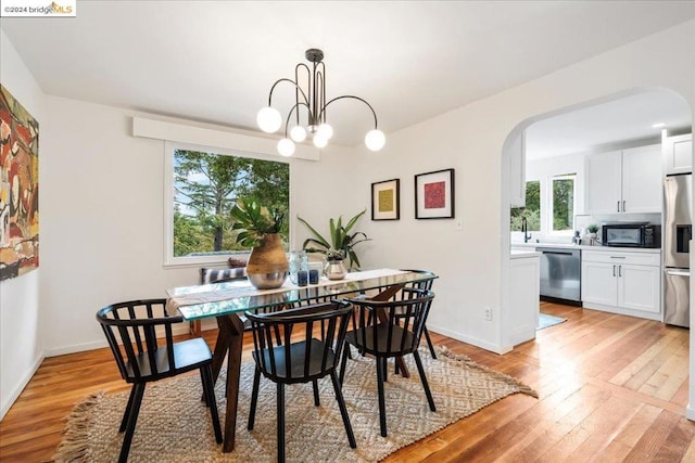 dining area featuring an inviting chandelier, sink, and light wood-type flooring