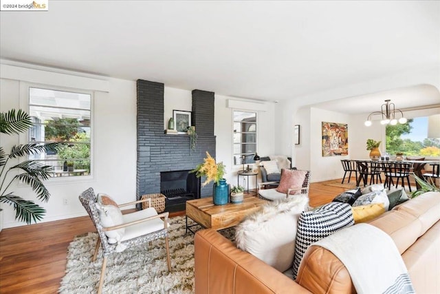 living room with wood-type flooring, a notable chandelier, and a fireplace