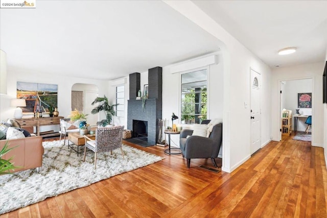 living room with a brick fireplace and hardwood / wood-style floors