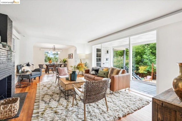 living room featuring a brick fireplace, hardwood / wood-style floors, and an inviting chandelier