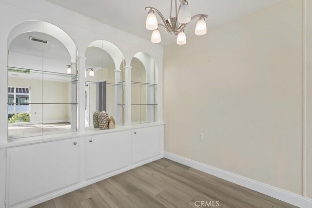 unfurnished dining area featuring light hardwood / wood-style floors and a chandelier