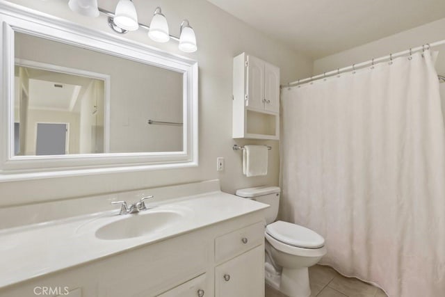 bathroom with toilet, vanity, and tile patterned flooring