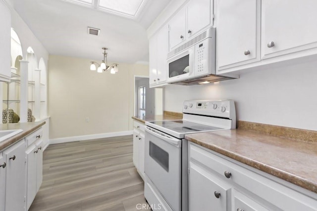 kitchen featuring white cabinetry, pendant lighting, a chandelier, and white appliances