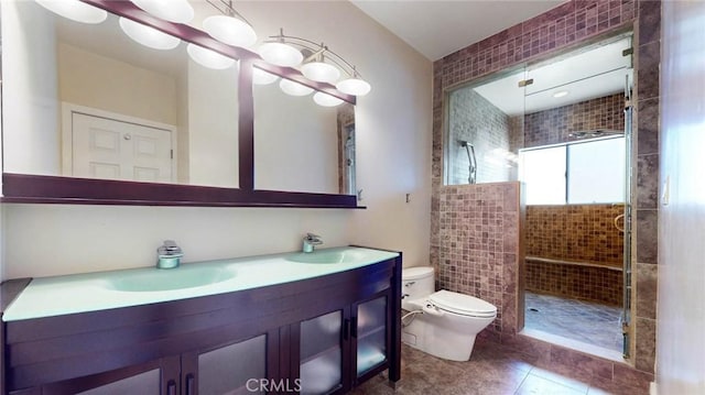 bathroom with toilet, vanity, tile patterned flooring, and tiled shower