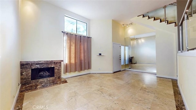 unfurnished living room featuring a high end fireplace and a high ceiling