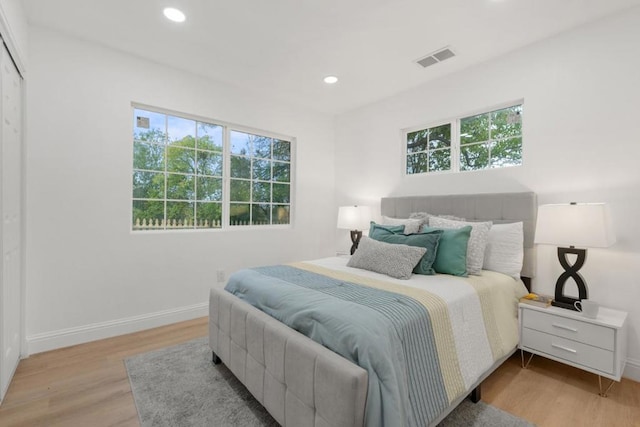 bedroom with light hardwood / wood-style floors and multiple windows