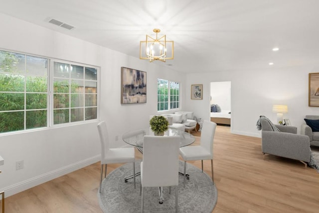 dining space featuring light wood-type flooring and an inviting chandelier