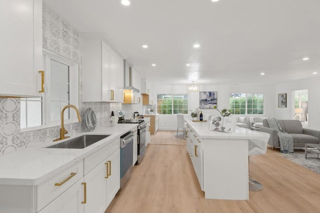 kitchen featuring white cabinetry, stainless steel appliances, a center island, and sink