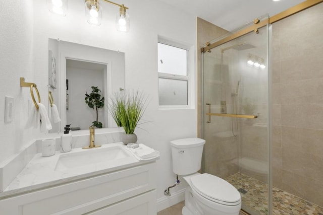 bathroom with toilet, vanity, and a shower with door