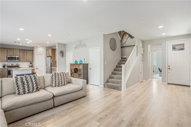 living room with light hardwood / wood-style floors and a notable chandelier