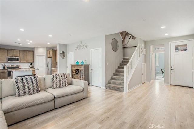 living area featuring recessed lighting, light wood-type flooring, baseboards, and stairs