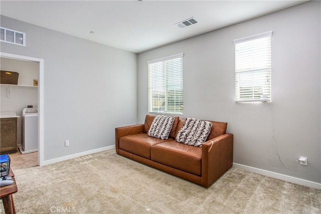 living area with light carpet, washer / clothes dryer, visible vents, and baseboards