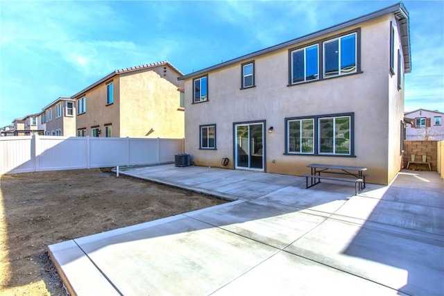 rear view of house with a patio area, a fenced backyard, central AC, and stucco siding