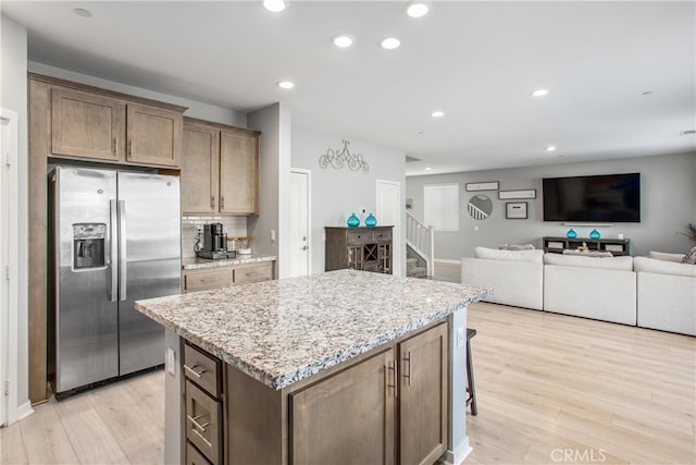 kitchen featuring stainless steel fridge with ice dispenser, a center island, light wood finished floors, and recessed lighting