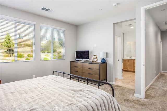 bedroom featuring a sink, light colored carpet, baseboards, and visible vents