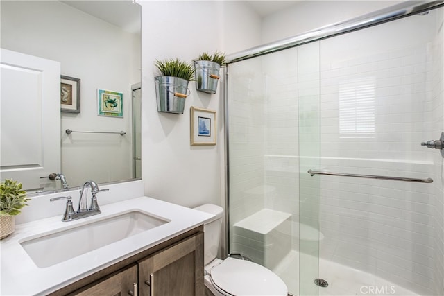 bathroom featuring a shower with shower door, toilet, and vanity