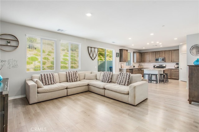 living area with visible vents, baseboards, light wood-type flooring, and recessed lighting