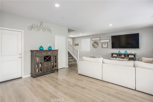 living room featuring wood finished floors, recessed lighting, baseboards, and stairs
