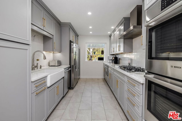 kitchen featuring appliances with stainless steel finishes, sink, wall chimney range hood, light tile patterned floors, and gray cabinets