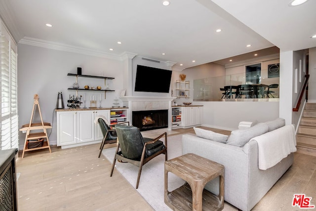 living room with crown molding, a high end fireplace, and light hardwood / wood-style flooring