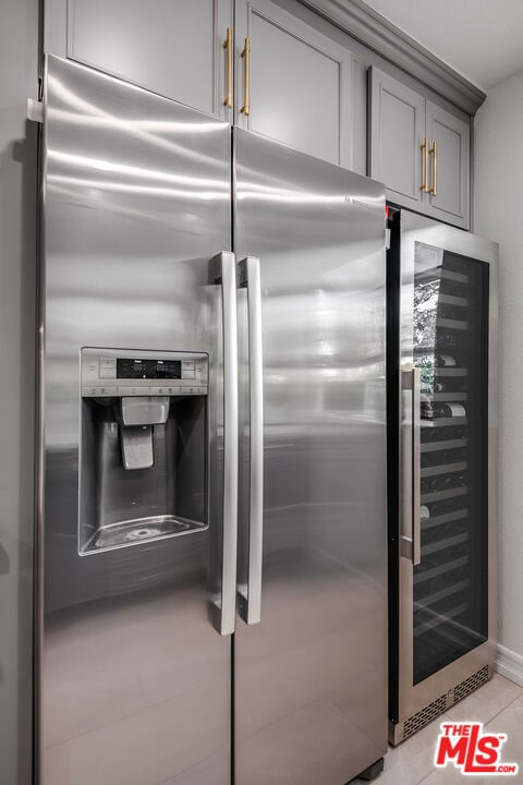 kitchen featuring gray cabinets, stainless steel fridge, light tile patterned floors, and wine cooler