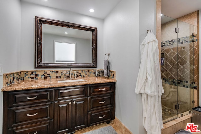 bathroom with decorative backsplash, vanity, and a shower with shower door