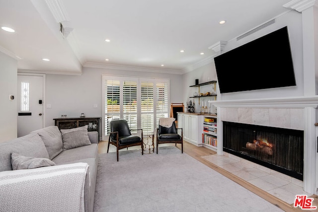 living room featuring light hardwood / wood-style floors, ornamental molding, and a tile fireplace