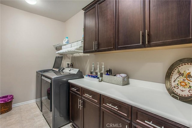 washroom featuring washer and dryer, light tile patterned floors, and cabinets