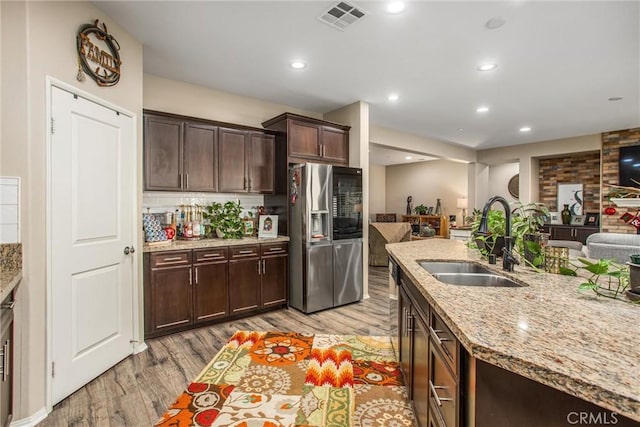 kitchen featuring light stone countertops, sink, light hardwood / wood-style flooring, and stainless steel fridge with ice dispenser