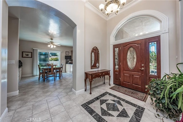 entrance foyer featuring baseboards, arched walkways, crown molding, and ceiling fan with notable chandelier