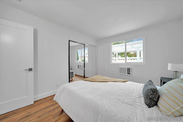 bedroom with a wall unit AC, light hardwood / wood-style flooring, and a closet