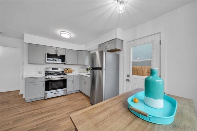 kitchen featuring appliances with stainless steel finishes, gray cabinetry, and light hardwood / wood-style flooring