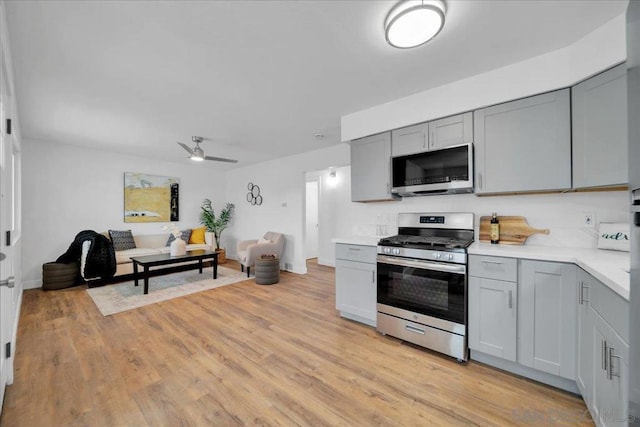 kitchen with ceiling fan, appliances with stainless steel finishes, gray cabinetry, and light hardwood / wood-style flooring