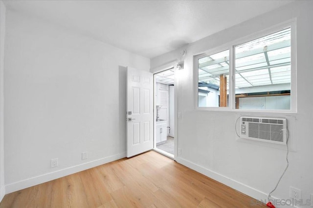 spare room featuring an AC wall unit, plenty of natural light, and light hardwood / wood-style flooring