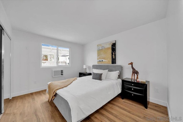 bedroom with an AC wall unit and light wood-type flooring