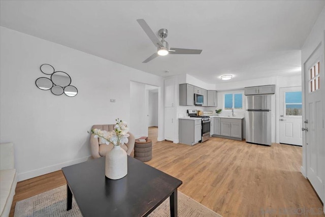 living room with ceiling fan and light hardwood / wood-style flooring