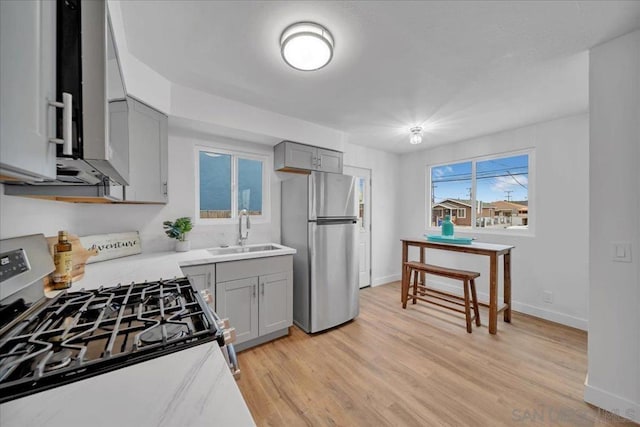 kitchen featuring sink, gray cabinetry, stainless steel appliances, and light hardwood / wood-style flooring