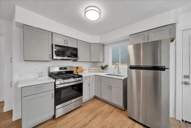 kitchen featuring sink, gray cabinetry, stainless steel appliances, and light hardwood / wood-style flooring