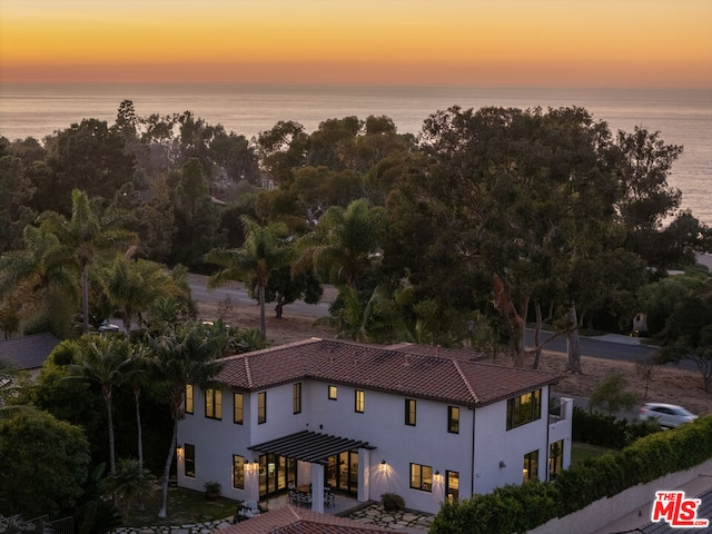 aerial view at dusk featuring a water view