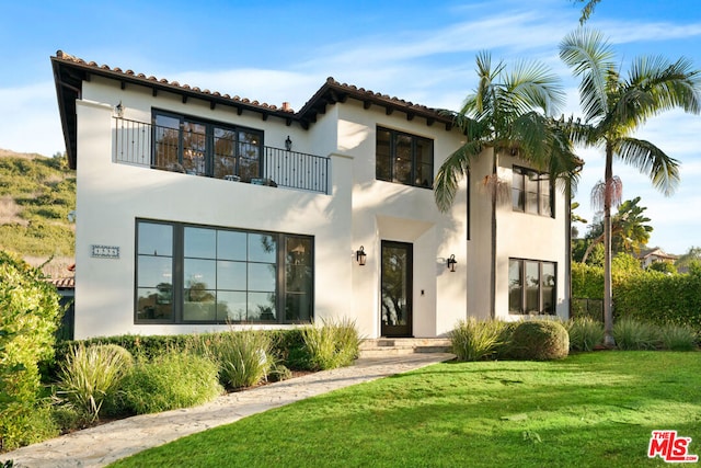 mediterranean / spanish home with a balcony and a front lawn