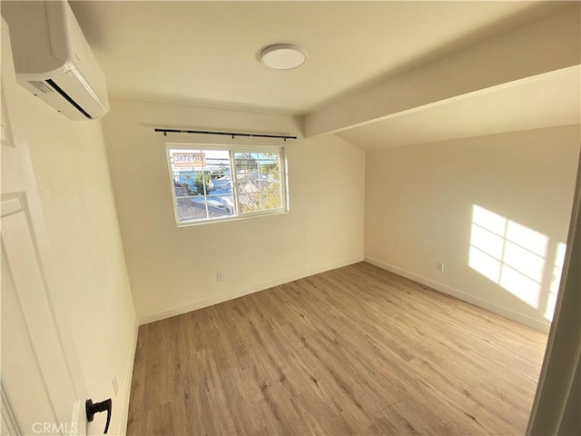 unfurnished room featuring lofted ceiling, an AC wall unit, and light hardwood / wood-style floors