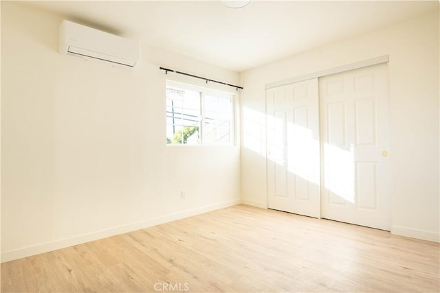 unfurnished bedroom featuring light wood-type flooring, a closet, and a wall mounted air conditioner