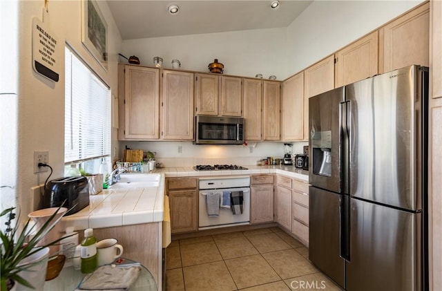 kitchen featuring stainless steel appliances, light brown cabinets, and tile counters