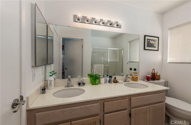 bathroom with toilet, vanity, and a shower with shower door