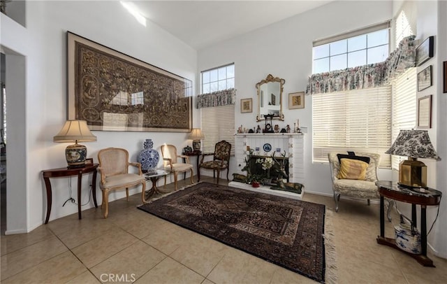 living area featuring a brick fireplace, a towering ceiling, and light tile patterned flooring