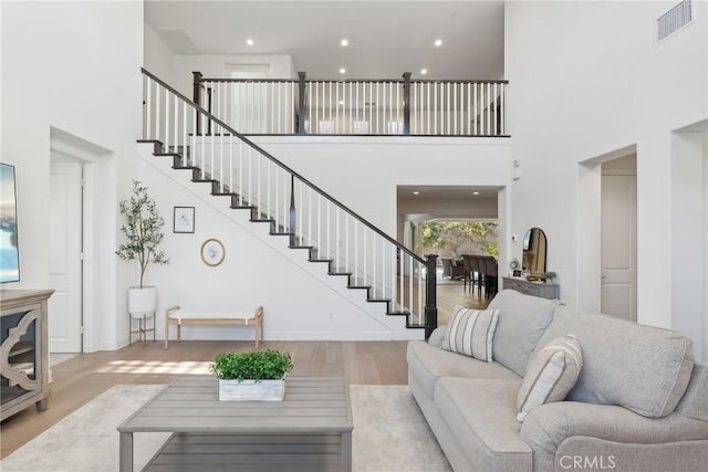 living room with a towering ceiling and light hardwood / wood-style floors